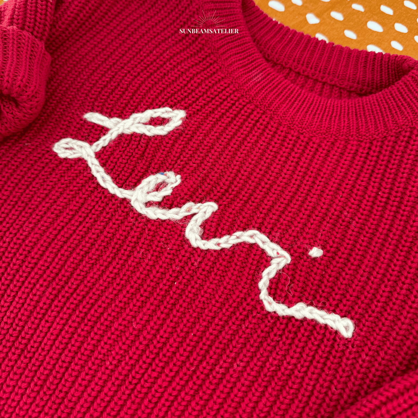 Detailansicht Namenspullover in Rot mit besticktem Schriftzug "Levi"
