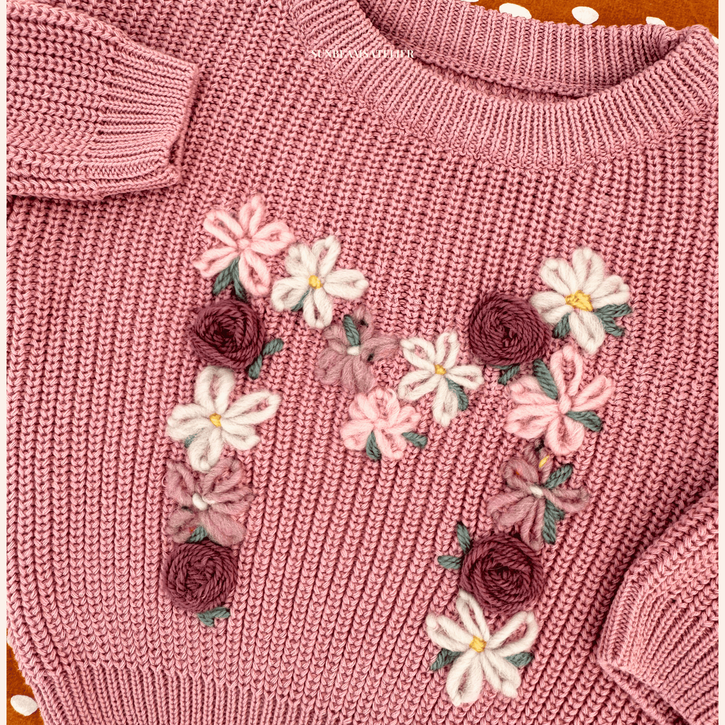 Detailansicht: Produktbild eines altrosanen Strickpullover mit einem M-Monogramm aus vielen kleinen Blumen und Rosen in Mauve, Pink und weiß
