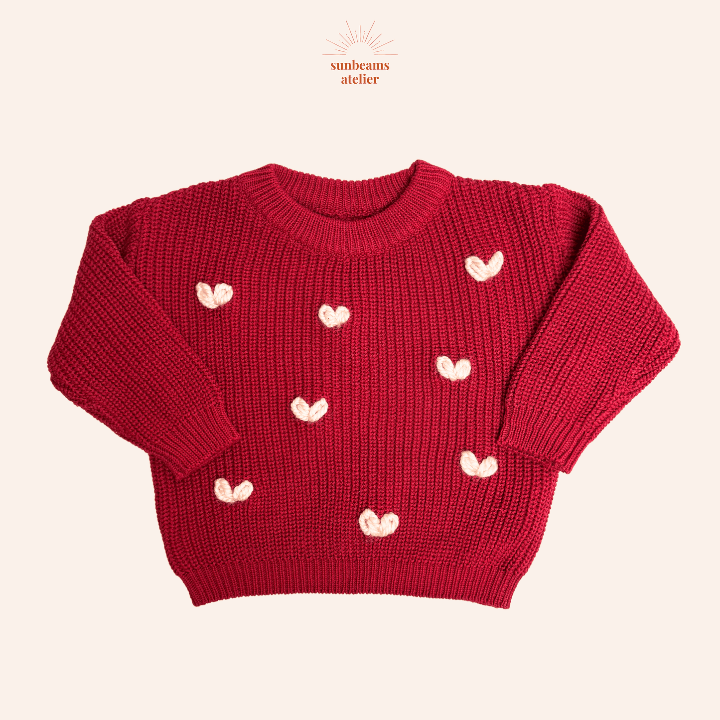 Produktbild mit einem roten Strickpullover und vielen großen rosa und hellen bestickten Herzchen mit chunky Garn