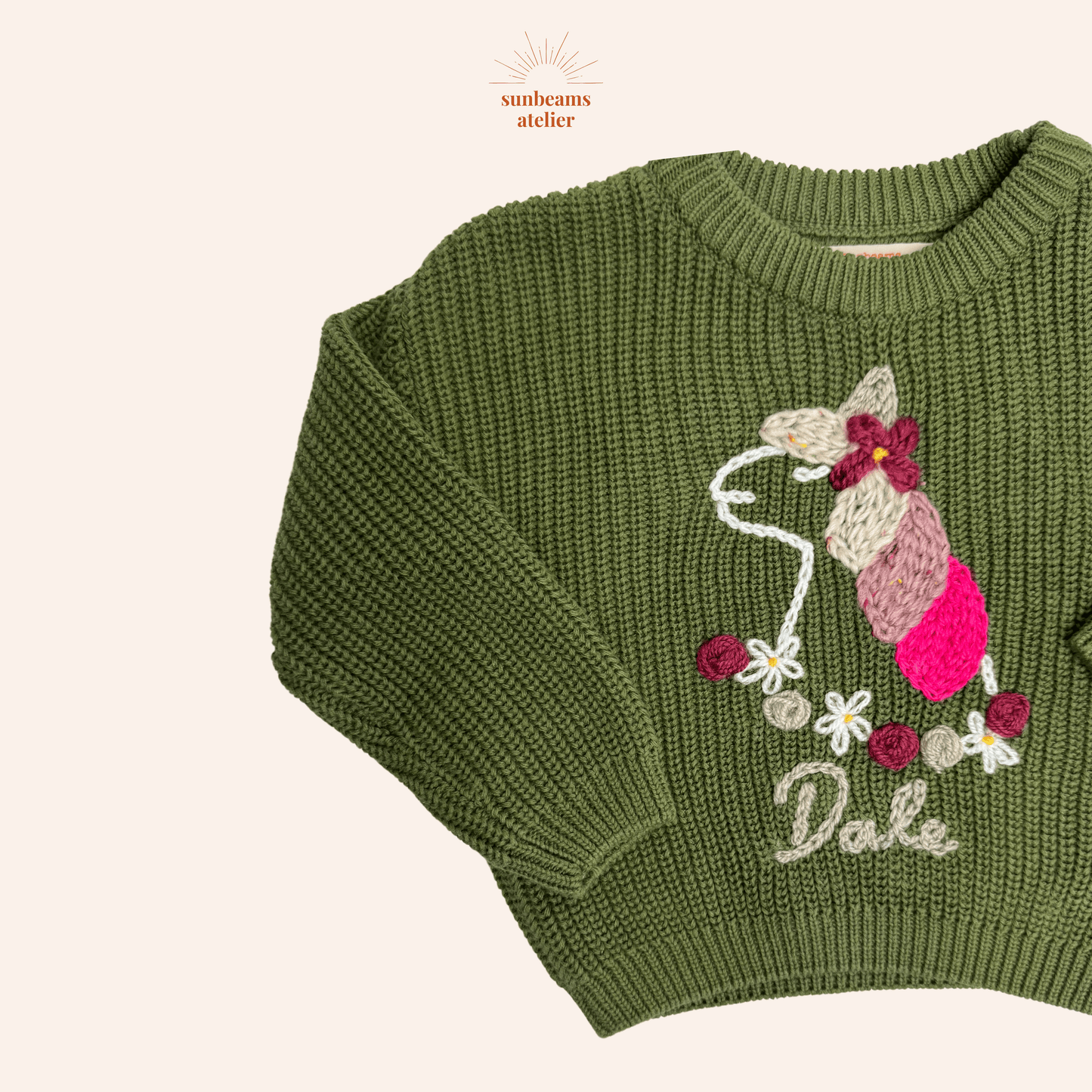 Strickpullover in green mit einem bestickten Einhorn und ein Blumenkranz aus Blüten und Rosen. Unten ist ein bestickter Schriftzug "Dale"