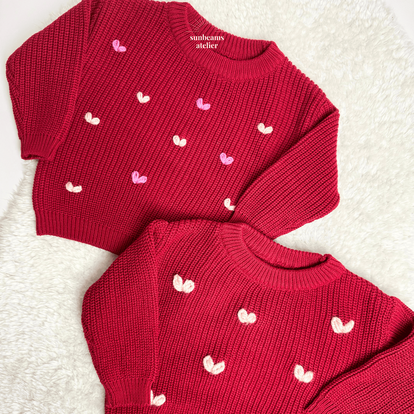 Zwei rote Strickpullover, bestickt mit kleinen Herzchen. Ein Pullover wurde mit regular Garn bestickt, der andere mit Chunky Garn.