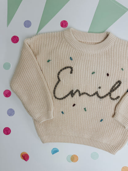 Namenspullover in Ivory mit besticktem Schriftzug "Emil" und Konfetti außenrum