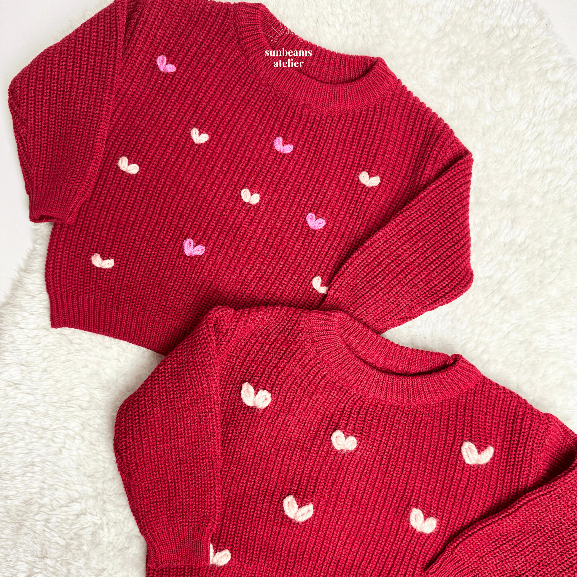 Zwei rote Strickpullover, bestickt mit kleinen Herzchen. Ein Pullover wurde mit regular Garn bestickt, der andere mit Chunky Garn.